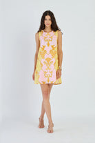 Woman wearing a yellow and pink patterned dress on a white background