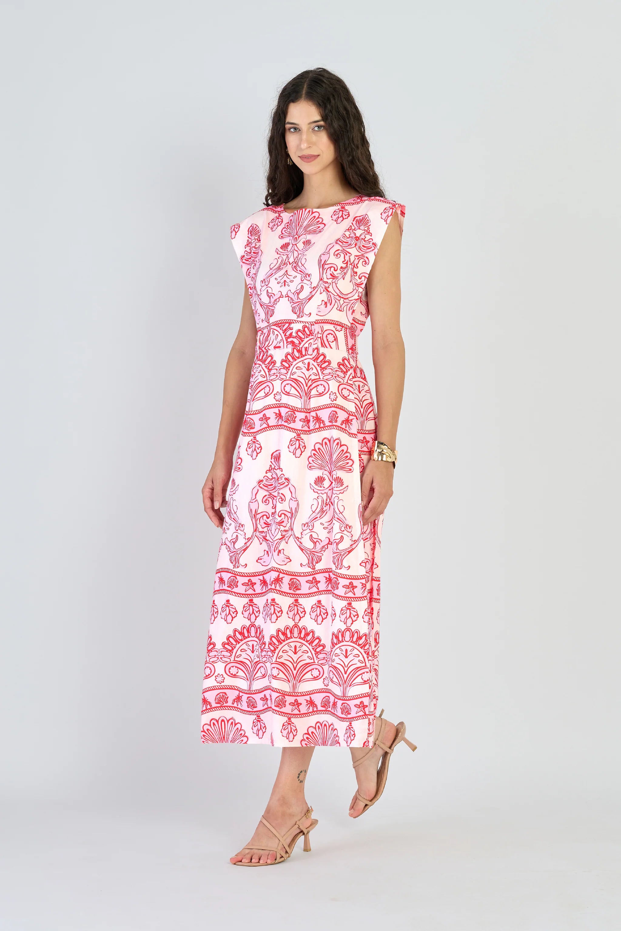 Woman wearing a pink and white patterned dress on a white background