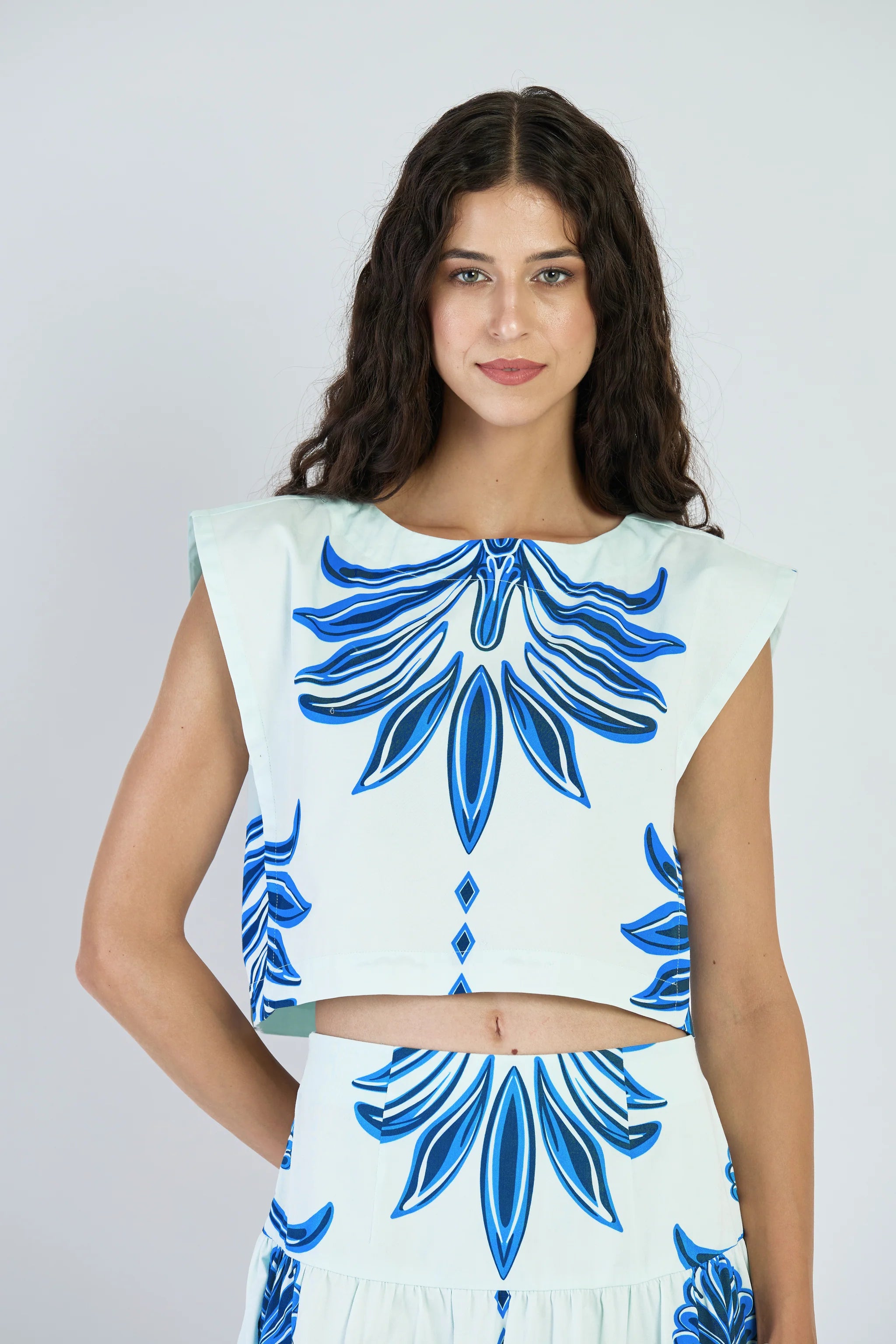 Woman wearing a dress with blue floral patterns on a plain background