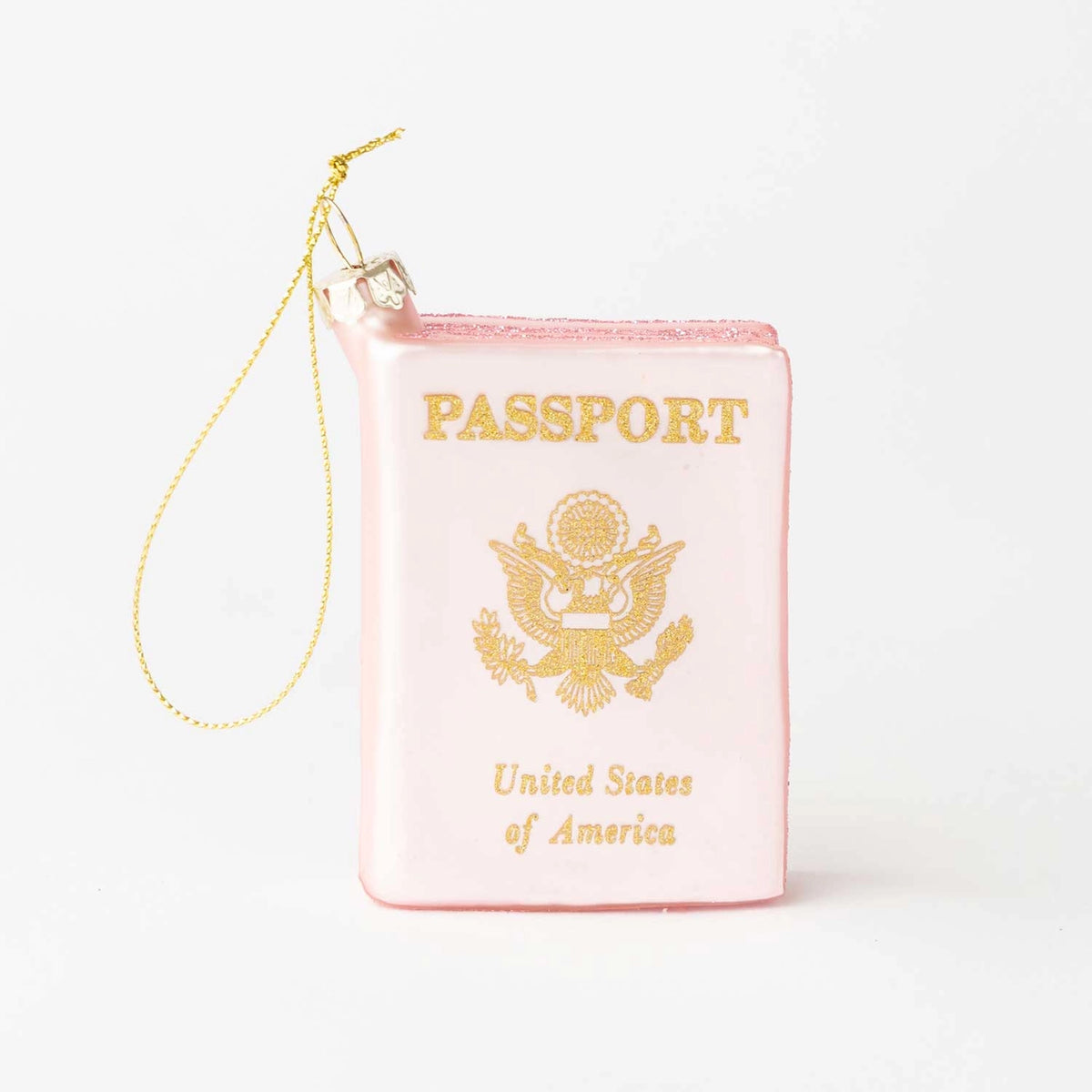 A novelty Christmas ornament shaped like a miniature pink passport with gold foil-style lettering and emblem, complete with a hanging gold string on a white background.