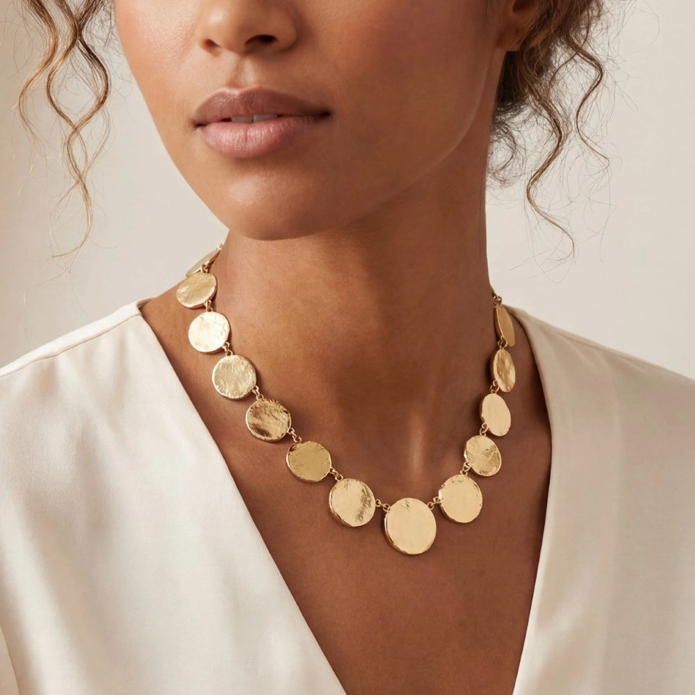 Woman wearing a gold necklace with a plain background