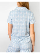 A woman shown from the back wearing a light blue short-sleeve collared top and matching pants with a white tree pattern, against a plain light background.