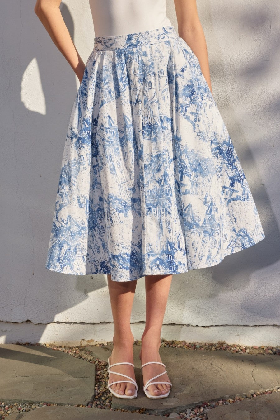 Person wearing a blue and white floral skirt against a neutral background