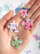 Hand holding colorful puzzle pieces with text and designs