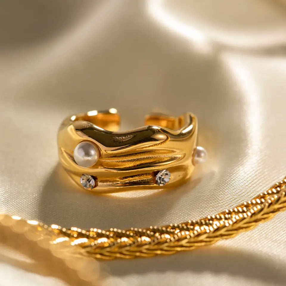 Gold ring with pearls and crystals on a gold surface