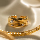 Gold ring with pearls and crystals on a gold surface