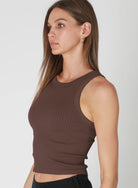 Woman wearing a brown ribbed tank top against a white background