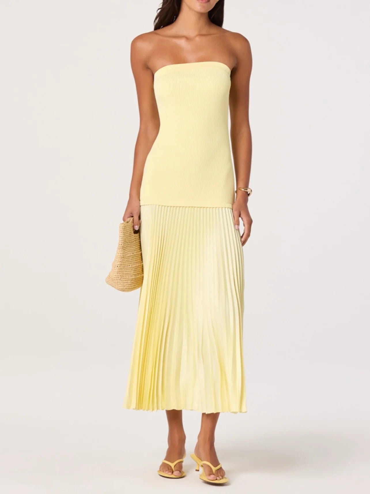 Woman wearing a strapless yellow dress with pleated skirt on a white background