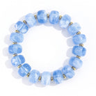A beaded stretch bracelet made of light blue marbled beads separated by small metallic gold spacer rings, shown on a plain white background.