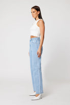 Woman wearing a white sleeveless top and light blue jeans on a white background
