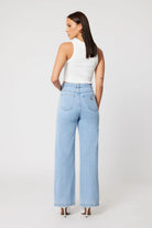 Woman wearing light blue jeans and a white top on a white background
