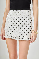 White polka dot skirt with black dots on a plain background