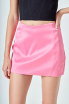 Person wearing a black top and pink skirt on a plain background