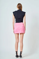 Person wearing a black sleeveless top and pink skirt on a white background