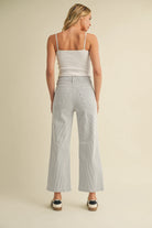 Woman wearing a white top and striped wide-leg pants on a beige background