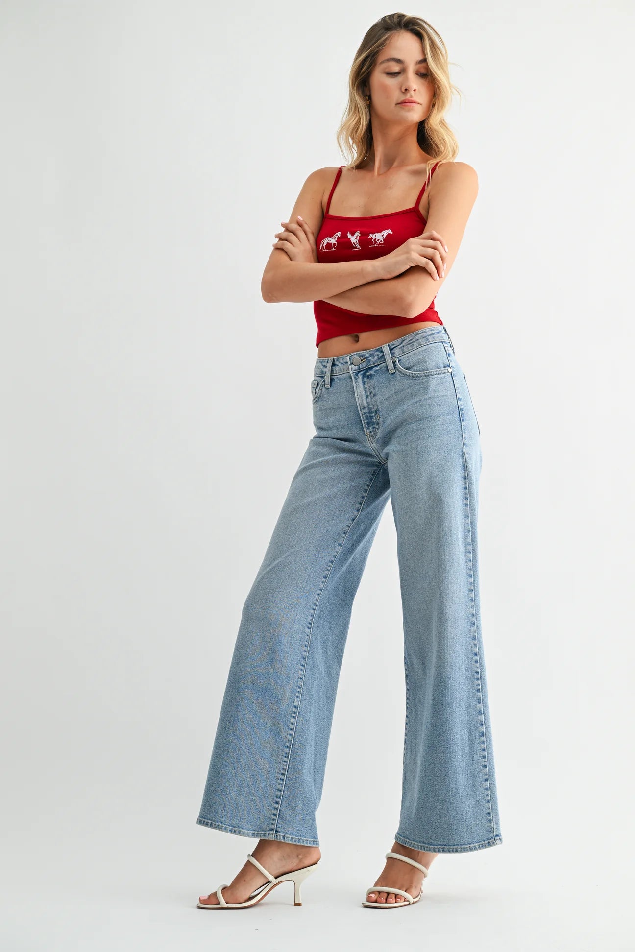 Woman wearing a red tank top and light blue jeans on a white background