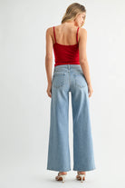 Woman wearing a red top and light blue jeans on a white background