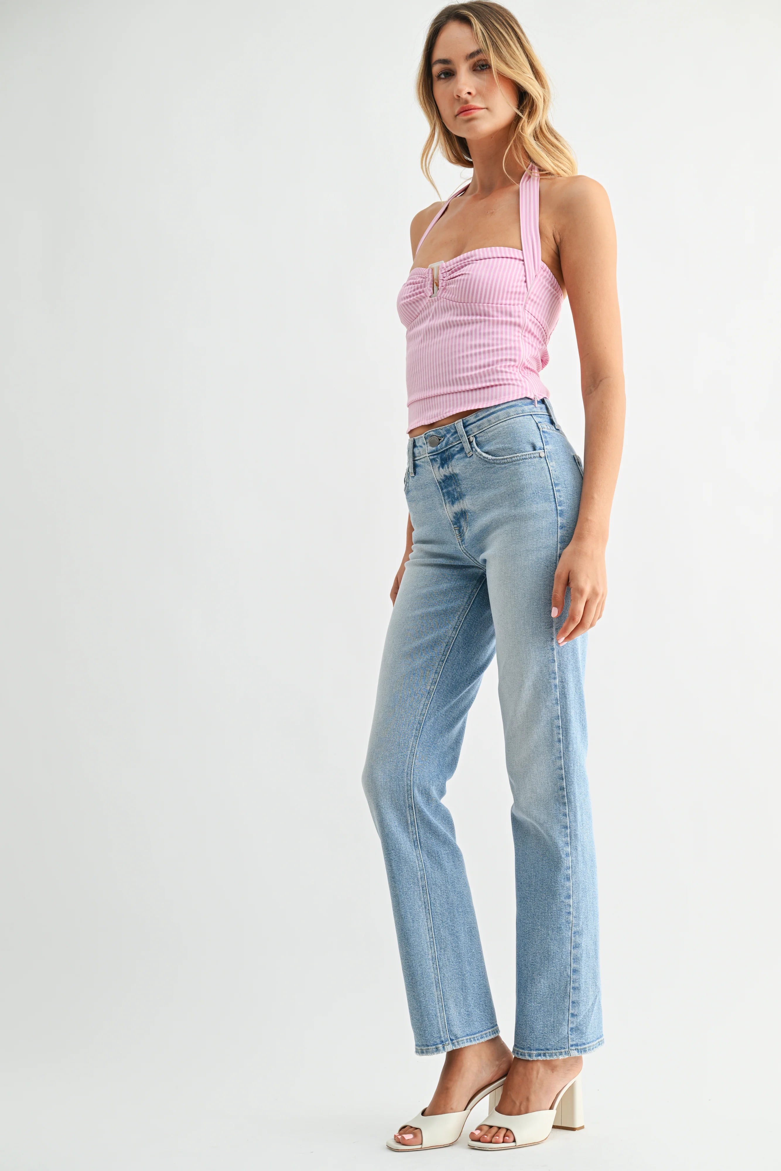 Woman wearing a pink top and light blue jeans on a white background
