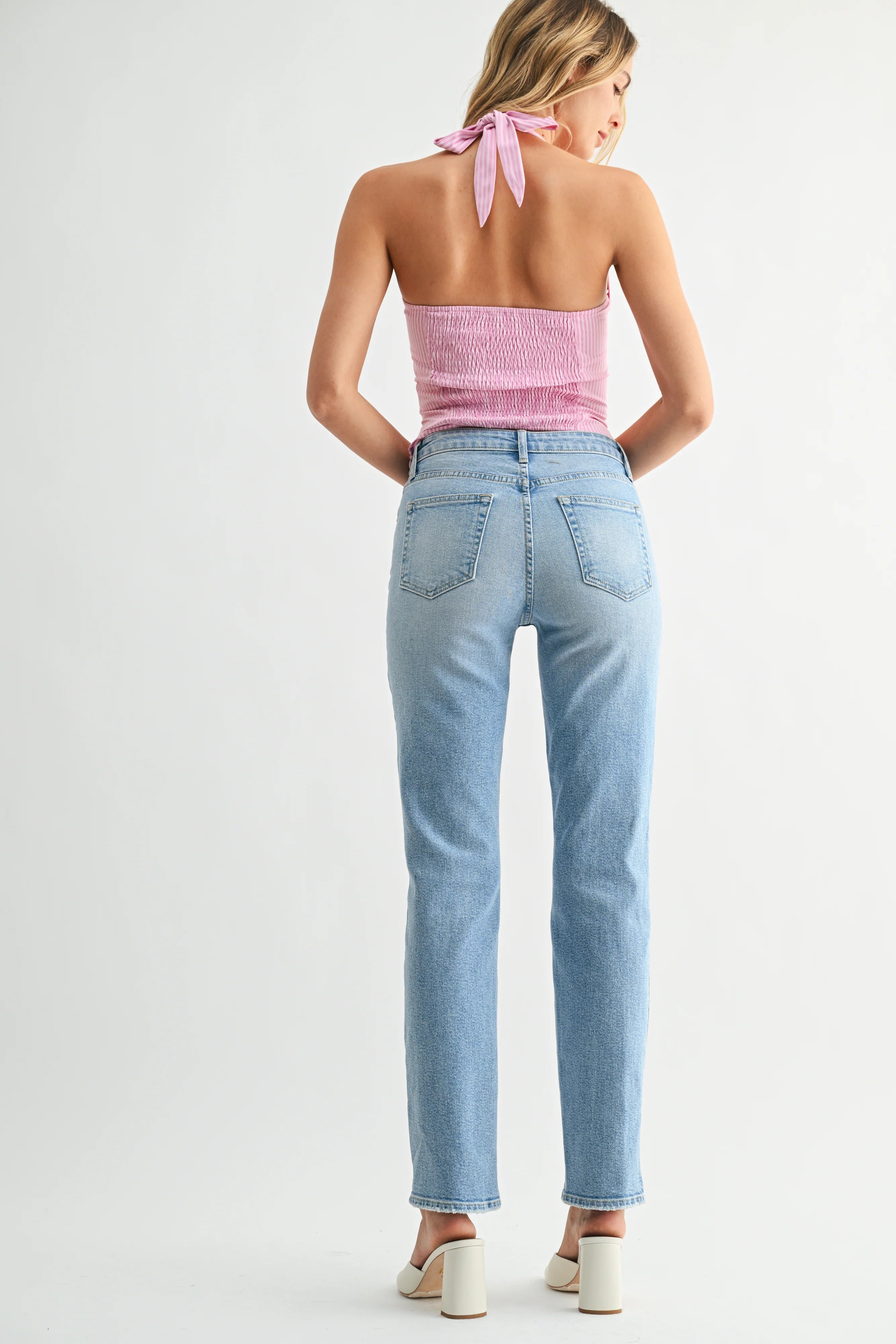 Woman wearing a pink top and light blue jeans on a white background