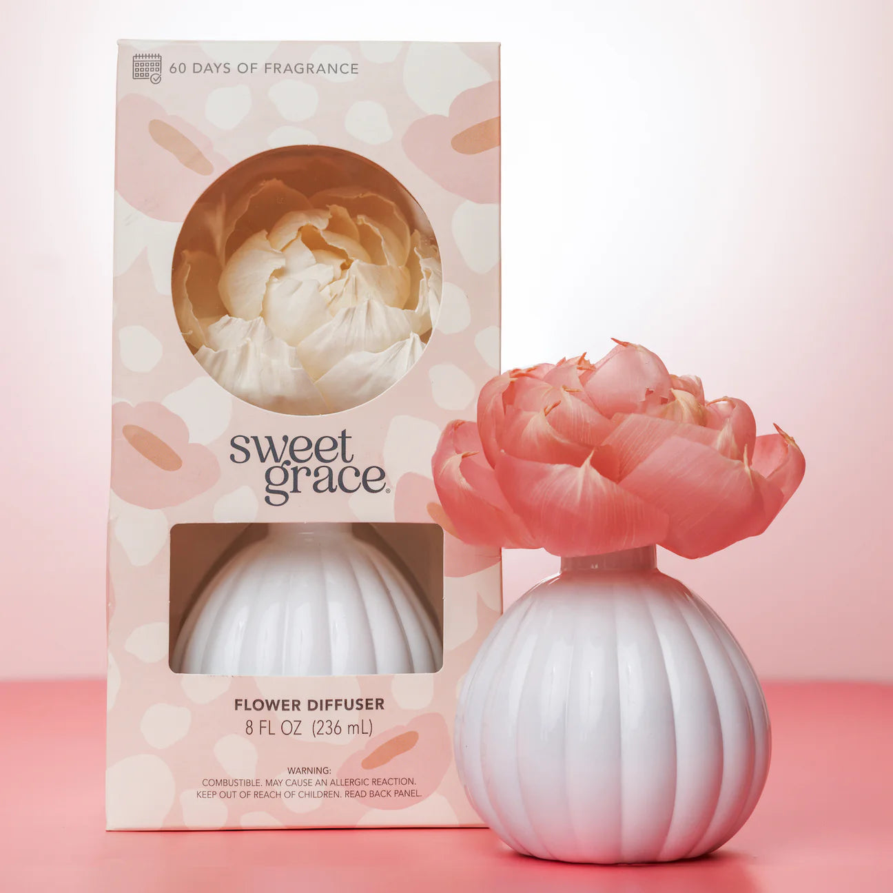 Sweet Grace flower diffuser with pink floral top next to its packaging on a pink background