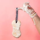 Hand holding a scrubber with soap suds against a pink background
