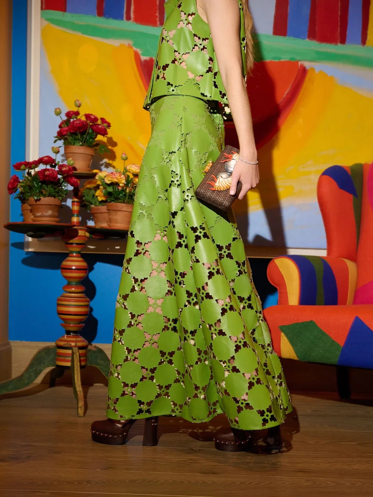 Person wearing a green patterned skirt with a colorful abstract painting in the background