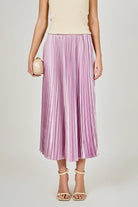 Person wearing a purple pleated skirt on a plain background