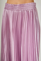 Close-up of a pink pleated skirt on a plain background