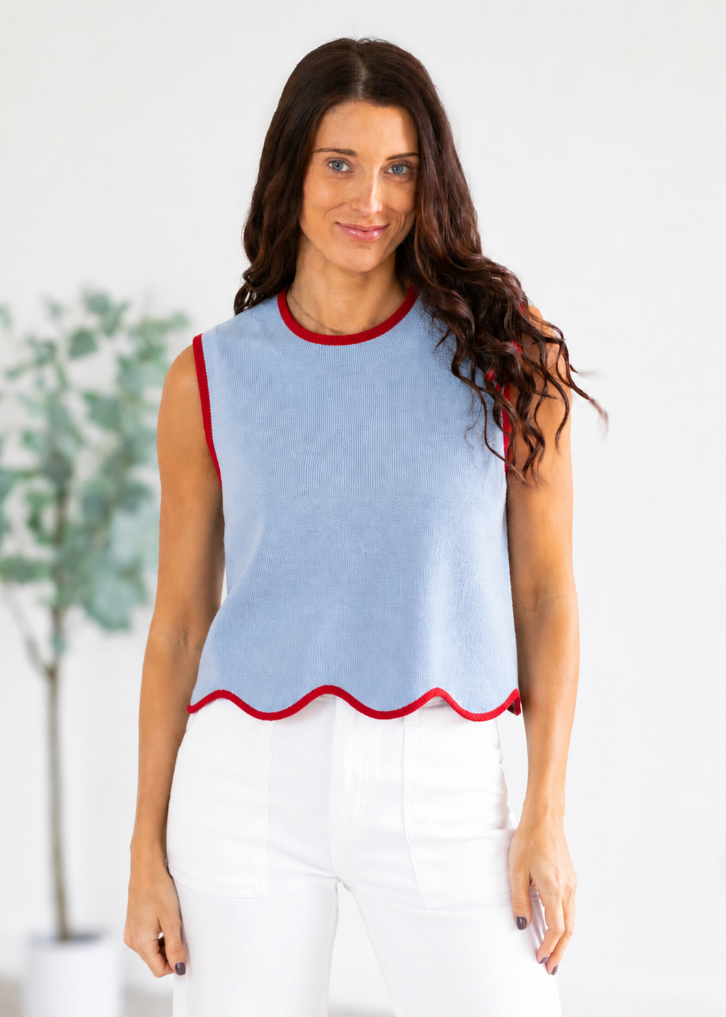 Woman wearing a light blue top with red trim against a white background