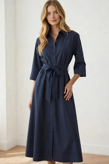 Woman wearing a navy blue dress with a belt against a white background
