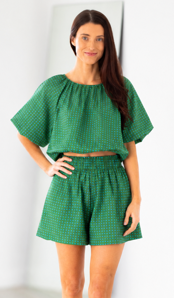Woman wearing a green outfit with a top and shorts on a white background