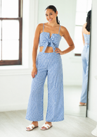 Woman wearing a blue and white checkered outfit in a room with a mirror.