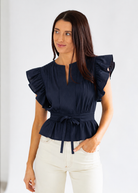 Woman wearing a navy blue blouse with ruffled sleeves on a white background