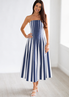 Woman wearing a strapless blue and white striped dress against a white background