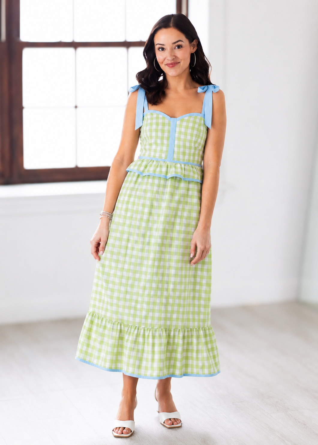 Woman wearing a green checkered dress with blue accents in a bright room.