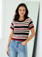Woman wearing a striped sweater and jeans against a plain background