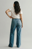 Person wearing blue jeans and a white t-shirt on a plain background
