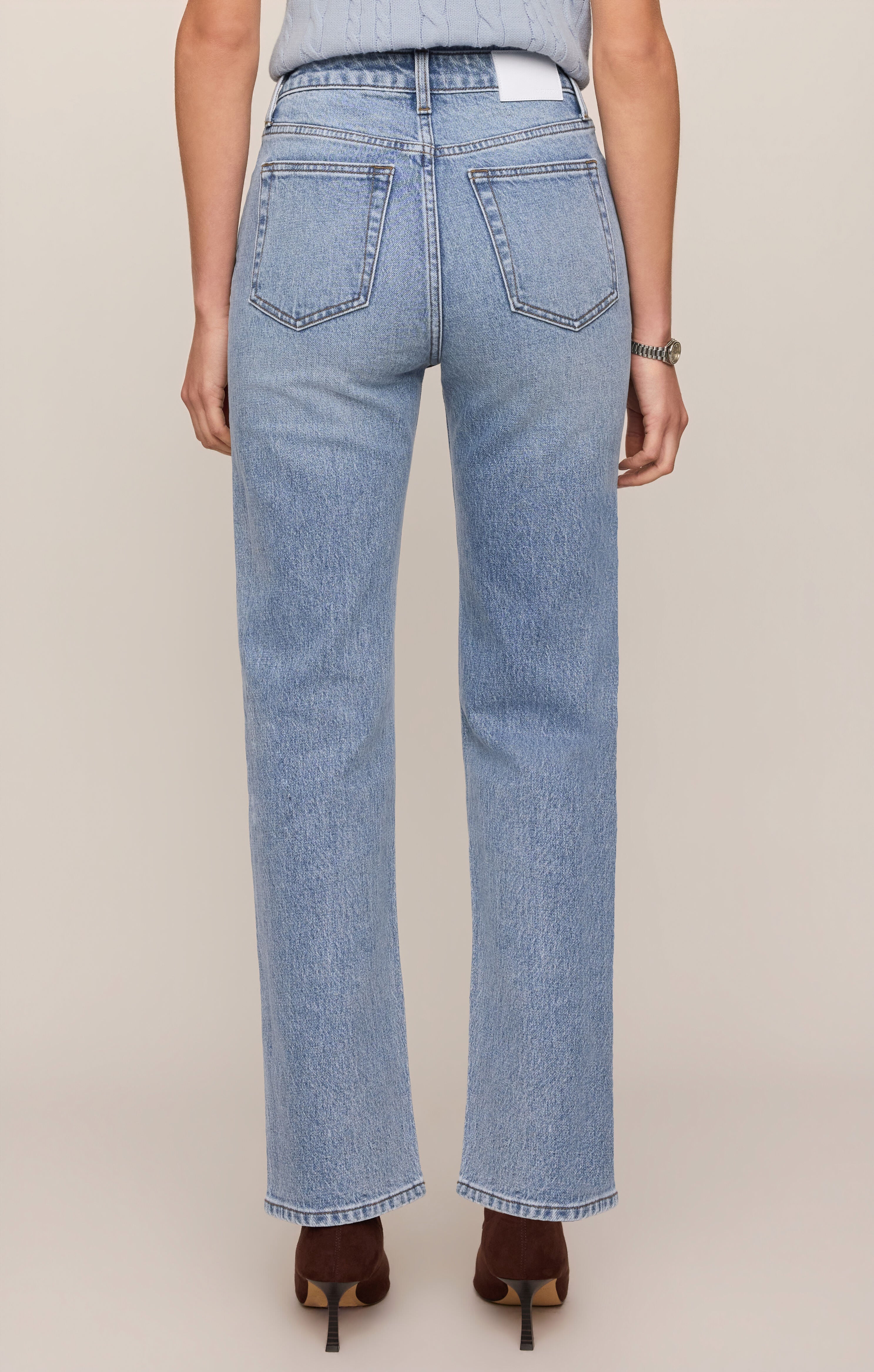 Light blue jeans worn by a person on a beige background
