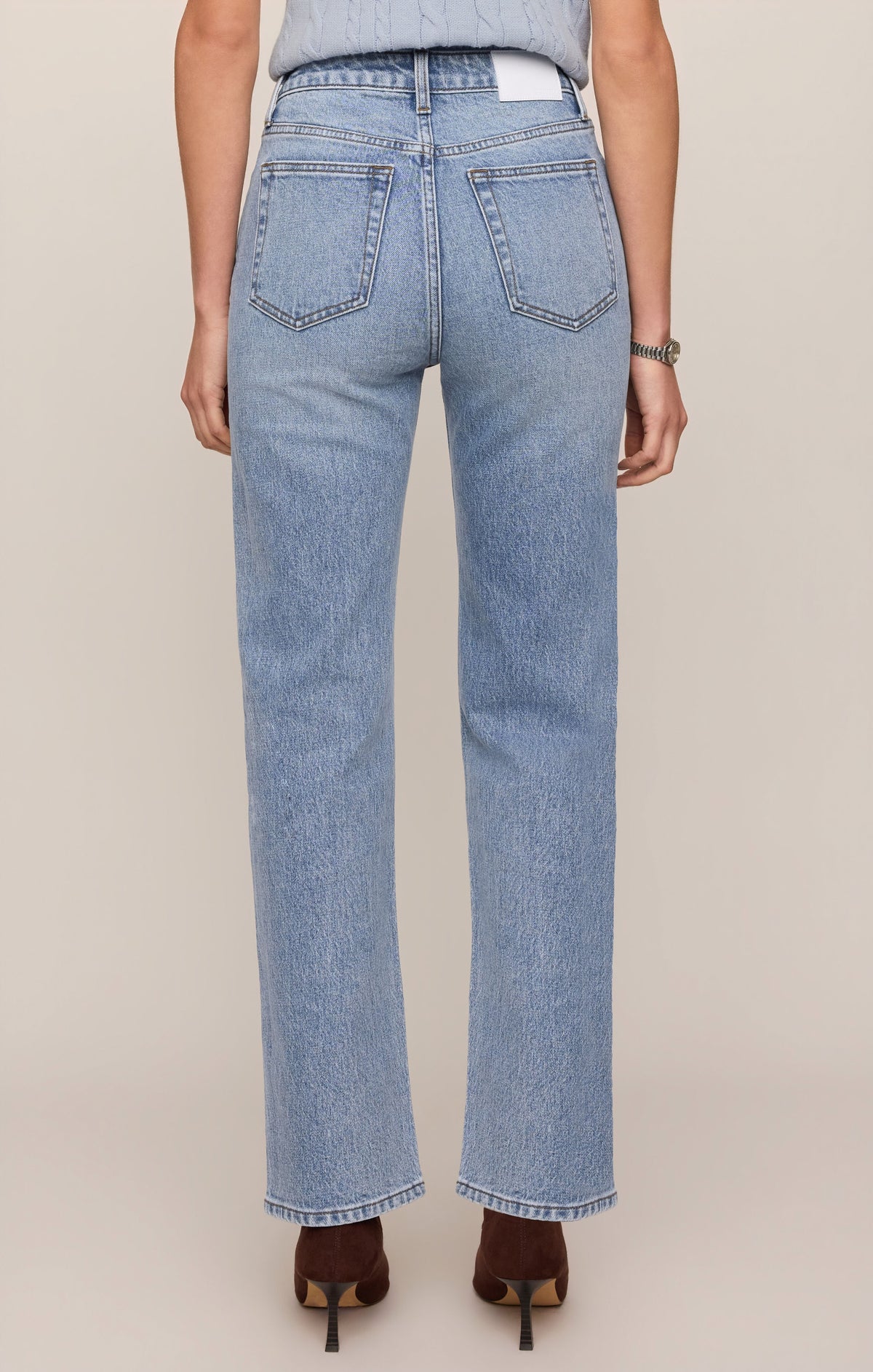 Light blue jeans worn by a person on a beige background