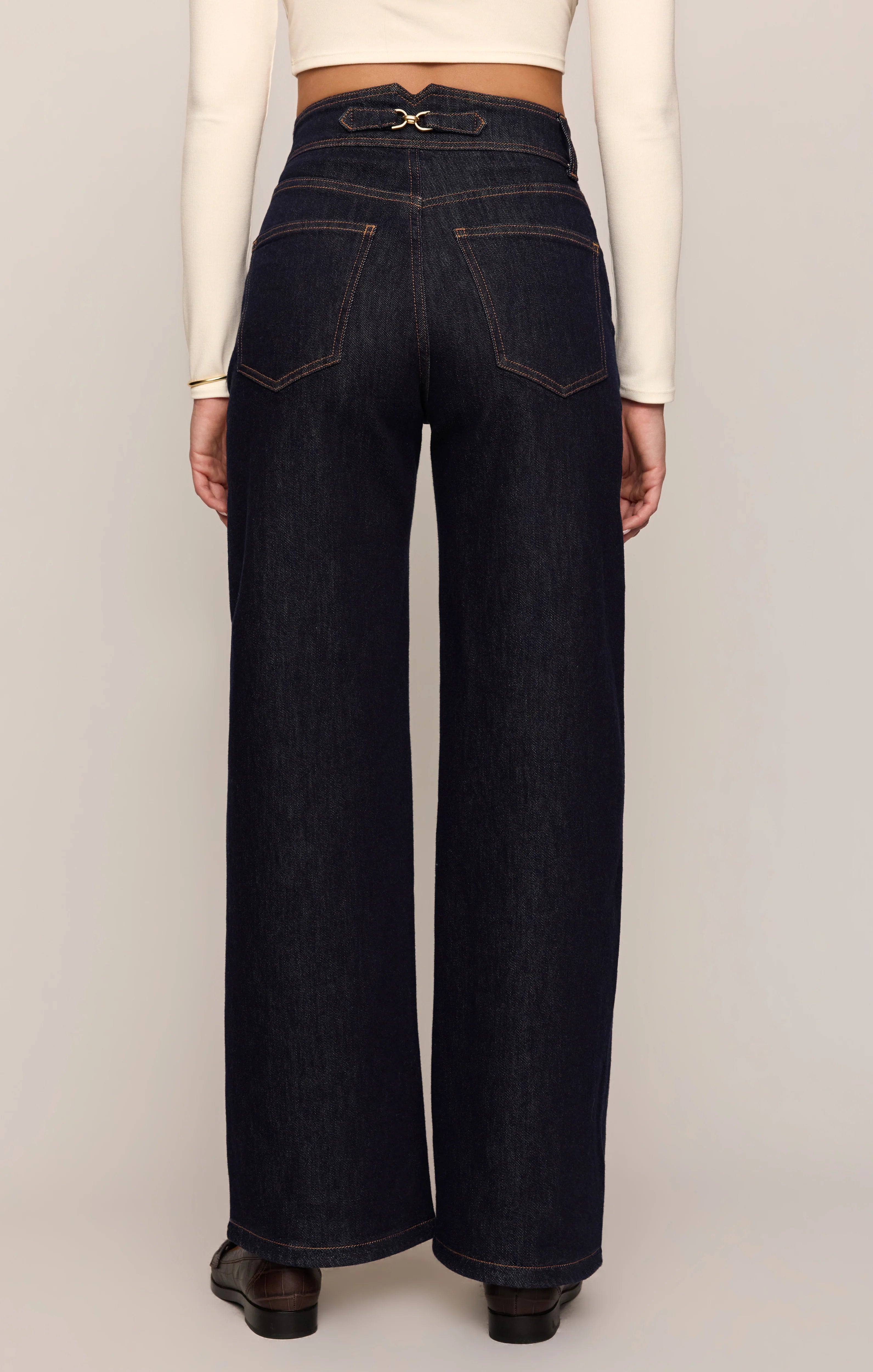 Person wearing dark blue jeans with a white background