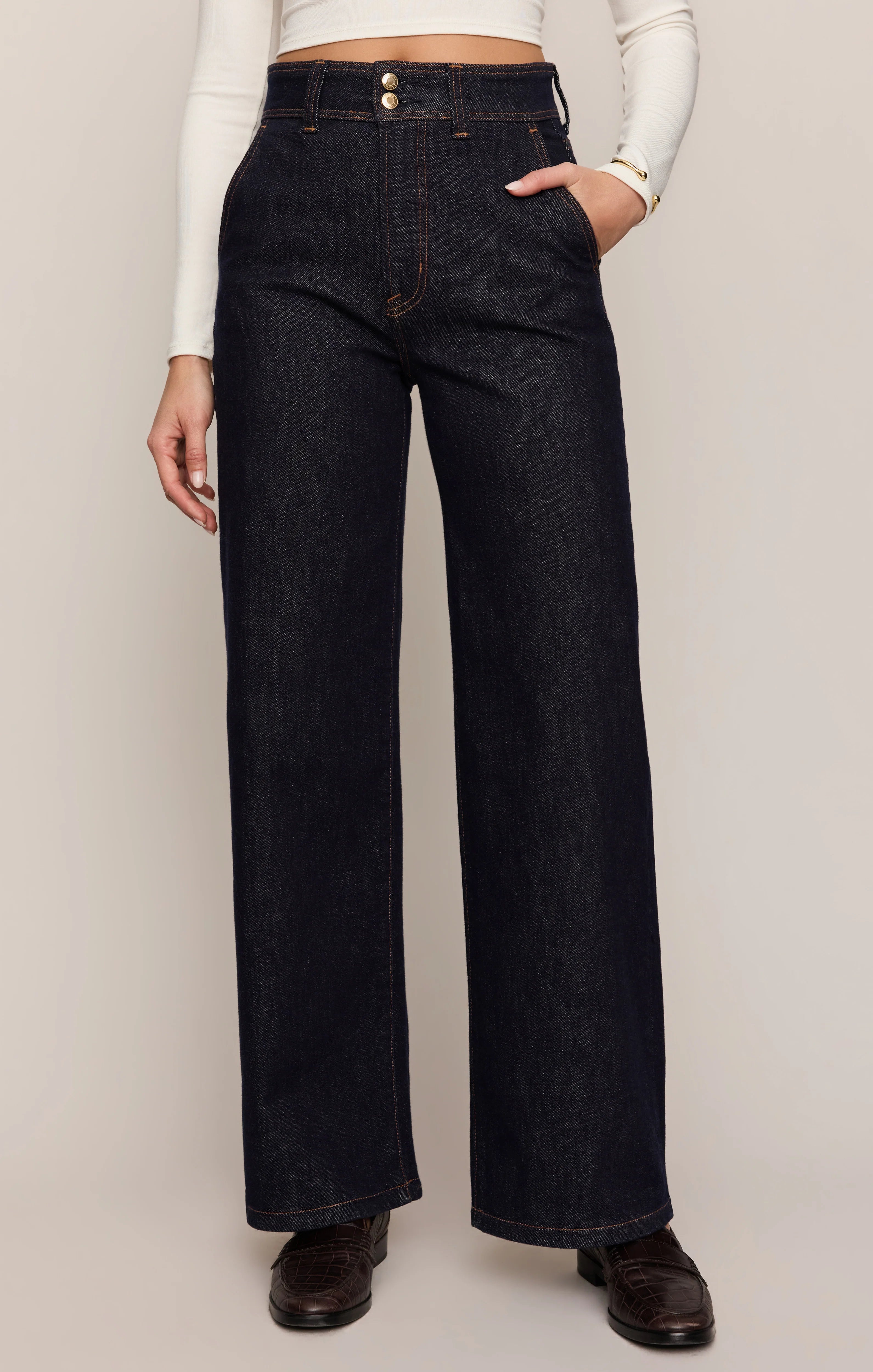 Person wearing dark blue wide-leg jeans on a plain background