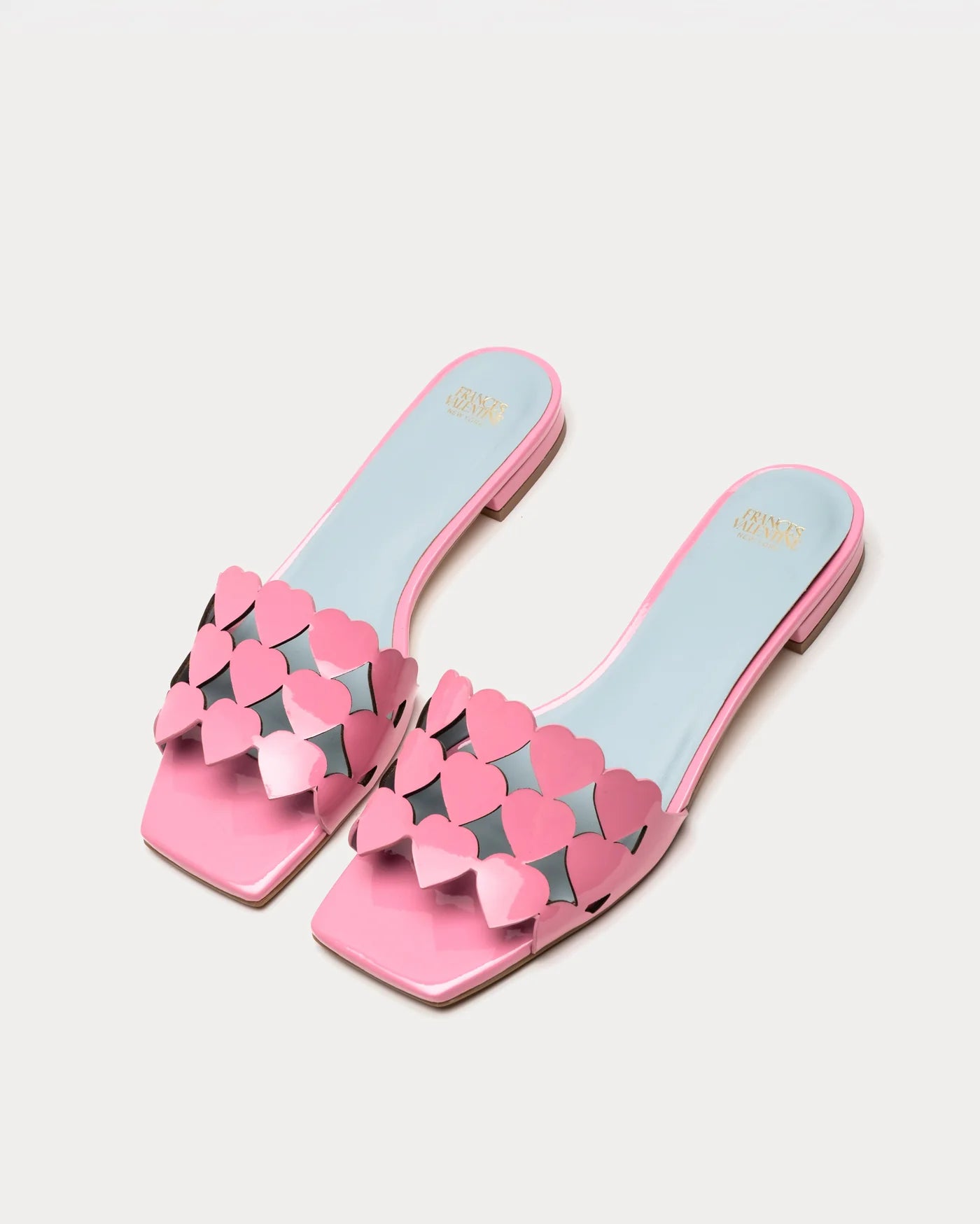 Pair of pink sandals with heart designs on a light gray background