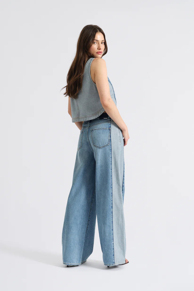 Woman wearing light blue jeans and a sleeveless top on a white background