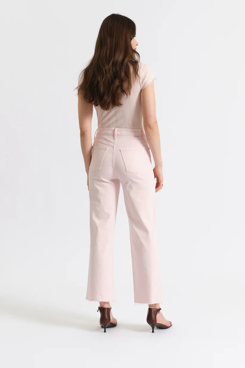 Woman wearing light pink pants and a white top on a white background