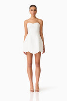 Woman wearing a white strapless dress on a white background