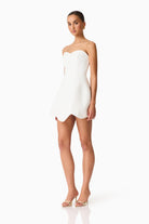 Woman wearing a strapless white dress on a white background