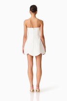 Woman wearing a strapless white dress on a white background