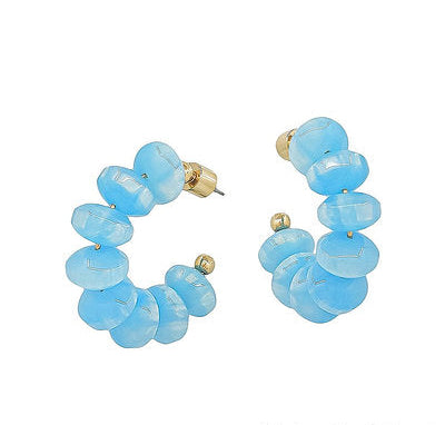 Pair of blue beaded hoop earrings on a white background
