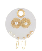 White earring holder with multiple sets of gold earrings with pearl accents on a white background