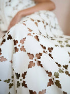 Close-up of a white lace garment with brown floral patterns.
